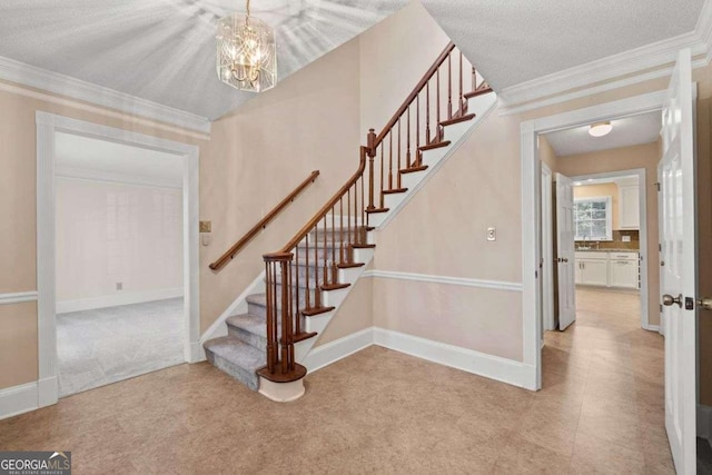 staircase featuring crown molding, carpet flooring, a textured ceiling, an inviting chandelier, and sink