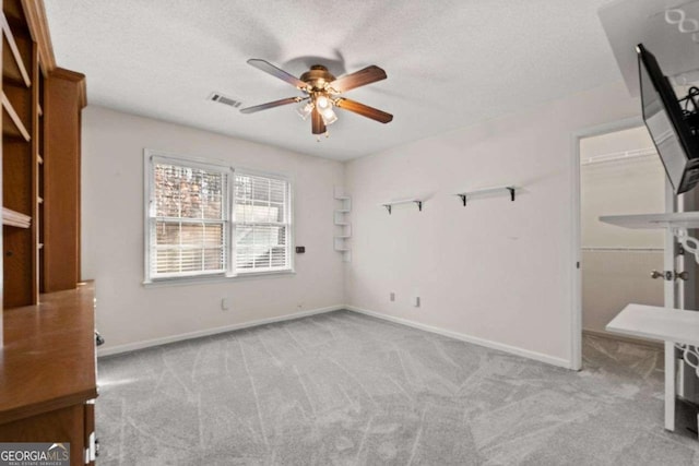 unfurnished room with a textured ceiling, ceiling fan, and light colored carpet