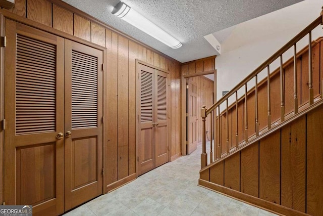 entryway with a textured ceiling and wood walls