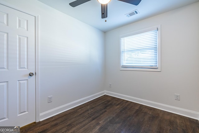 unfurnished room with dark wood-style floors, baseboards, visible vents, and a ceiling fan