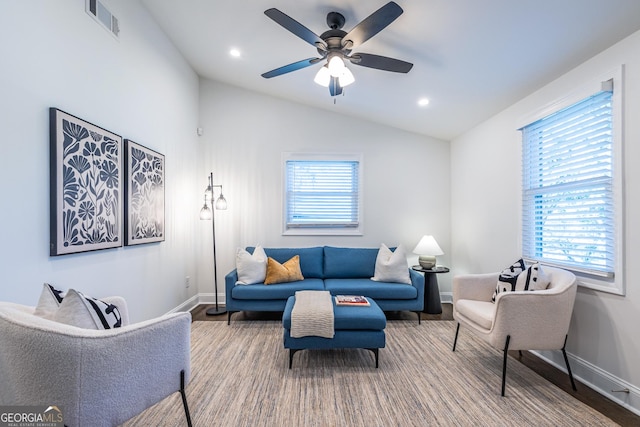 living room featuring plenty of natural light, visible vents, vaulted ceiling, and baseboards