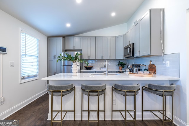 kitchen with dark wood finished floors, gray cabinets, appliances with stainless steel finishes, a sink, and a peninsula