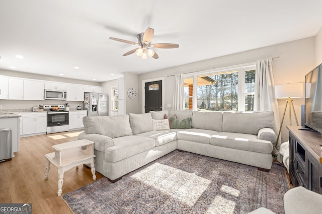 living room featuring ceiling fan and light hardwood / wood-style floors