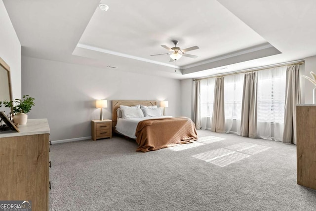 carpeted bedroom with a raised ceiling and ceiling fan