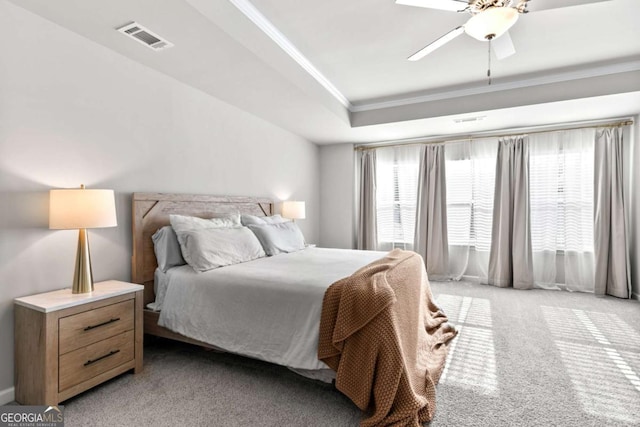 carpeted bedroom with ceiling fan, a raised ceiling, and crown molding