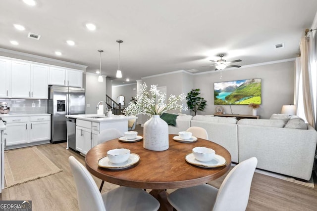 dining space with light hardwood / wood-style flooring, ceiling fan, ornamental molding, and sink