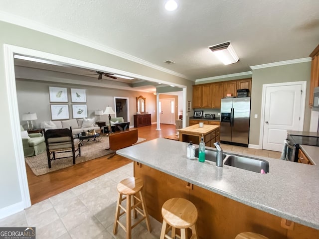 kitchen featuring a breakfast bar, sink, crown molding, a textured ceiling, and appliances with stainless steel finishes