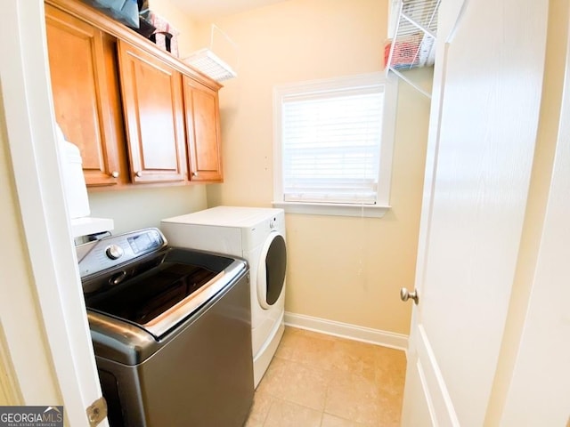 laundry room featuring washer and dryer, cabinets, and light tile patterned floors