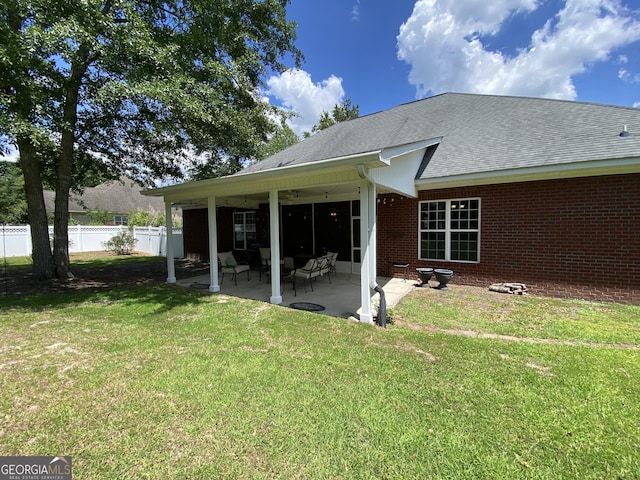 rear view of property featuring ceiling fan, a patio area, and a lawn