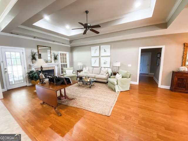 living room featuring hardwood / wood-style flooring, ceiling fan, a raised ceiling, and a fireplace