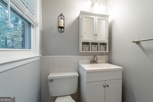 bathroom with toilet, tile walls, and vanity