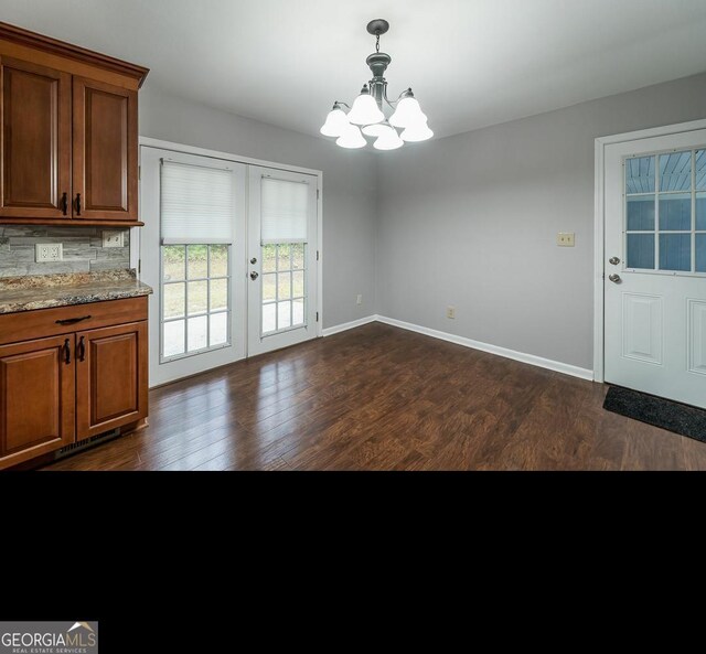 unfurnished dining area with an inviting chandelier, dark hardwood / wood-style flooring, and french doors