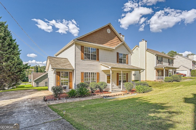 view of property with covered porch, a garage, and a front lawn