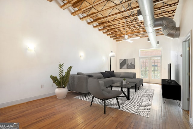 living room featuring hardwood / wood-style flooring, a high ceiling, french doors, and ceiling fan