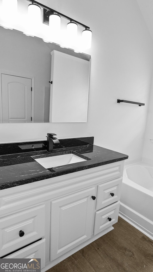 bathroom with a tub to relax in, vanity, and hardwood / wood-style flooring