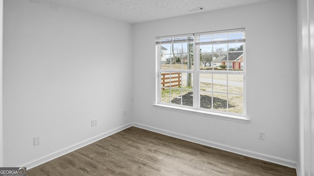 spare room with wood-type flooring and a textured ceiling