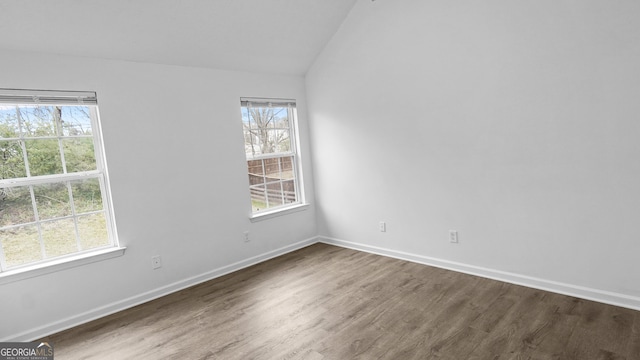 spare room featuring hardwood / wood-style flooring and lofted ceiling