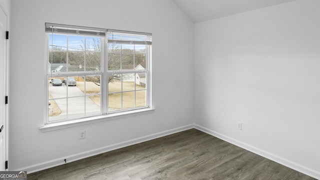 spare room featuring plenty of natural light, dark hardwood / wood-style floors, and vaulted ceiling