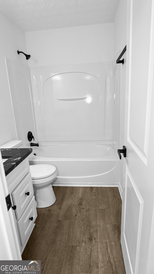 full bathroom featuring vanity, a textured ceiling, bathing tub / shower combination, hardwood / wood-style floors, and toilet