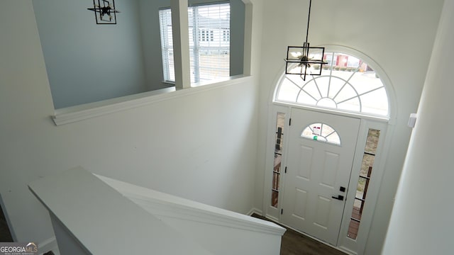 entryway featuring a high ceiling, an inviting chandelier, a wealth of natural light, and dark wood-type flooring