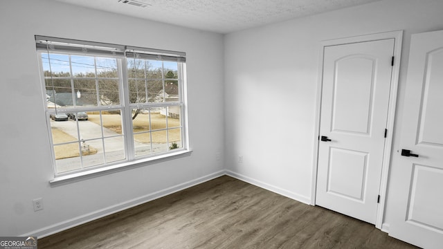 spare room featuring a textured ceiling and dark hardwood / wood-style floors