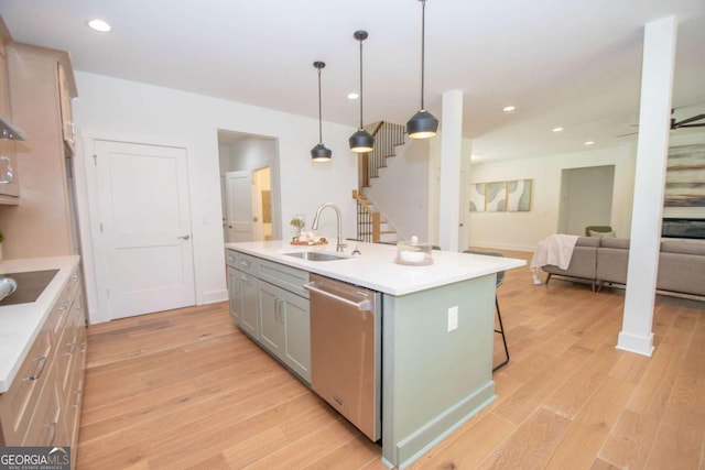 kitchen with pendant lighting, dishwasher, sink, an island with sink, and light hardwood / wood-style floors