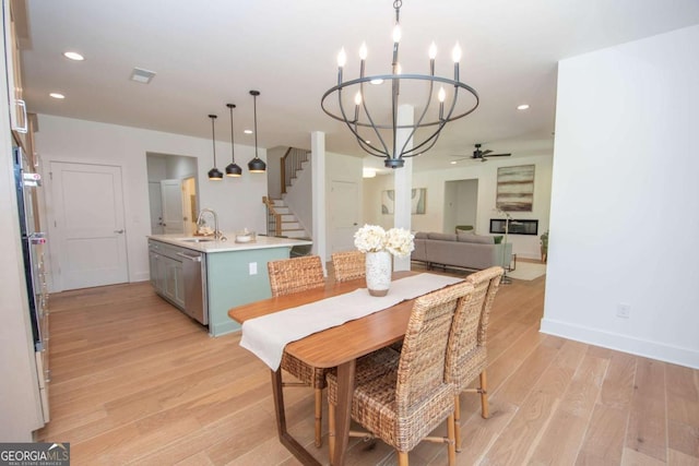 dining room with ceiling fan with notable chandelier, light hardwood / wood-style floors, and sink