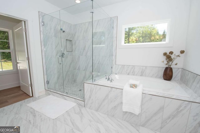 bathroom featuring a healthy amount of sunlight and separate shower and tub