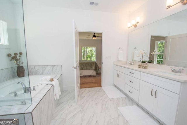 bathroom featuring vanity, a relaxing tiled tub, and ceiling fan