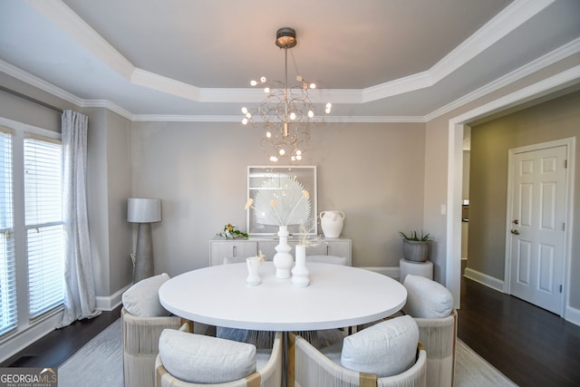 dining area featuring an inviting chandelier, a raised ceiling, and dark hardwood / wood-style floors