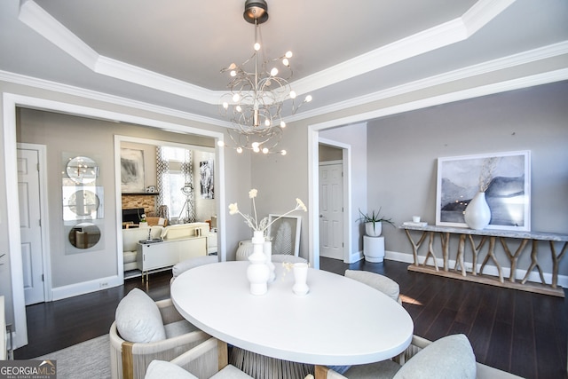 dining room featuring ornamental molding, dark wood-type flooring, a fireplace, and a tray ceiling