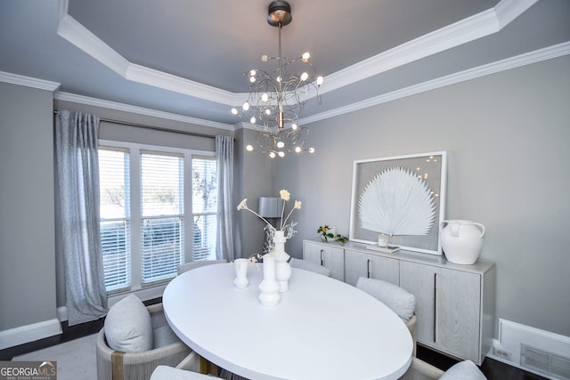 dining room featuring a raised ceiling, ornamental molding, and a chandelier