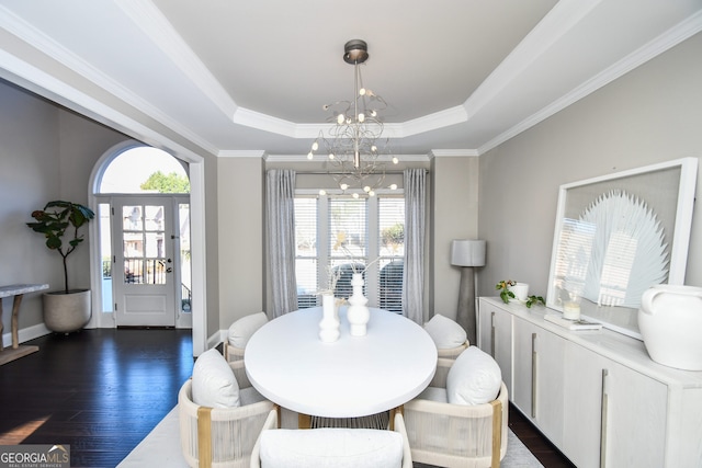 dining room featuring ornamental molding, a tray ceiling, an inviting chandelier, and dark wood-type flooring