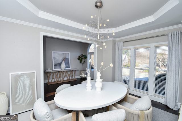 dining area with a raised ceiling, hardwood / wood-style flooring, crown molding, and a notable chandelier