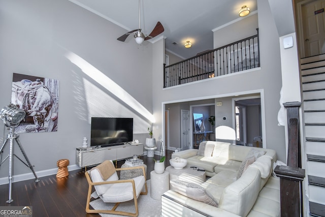 living room with ceiling fan, hardwood / wood-style floors, a high ceiling, and ornamental molding