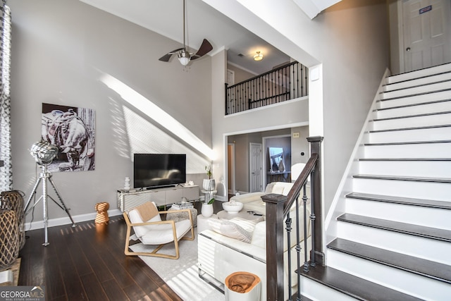 living room with ceiling fan, wood-type flooring, and a high ceiling