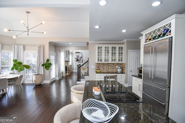 kitchen with pendant lighting, white cabinets, decorative backsplash, black electric cooktop, and stainless steel built in refrigerator