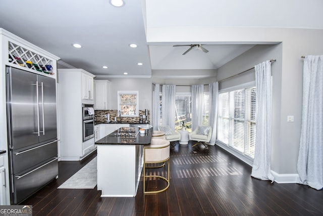 kitchen with a center island, stainless steel appliances, a kitchen breakfast bar, tasteful backsplash, and white cabinets