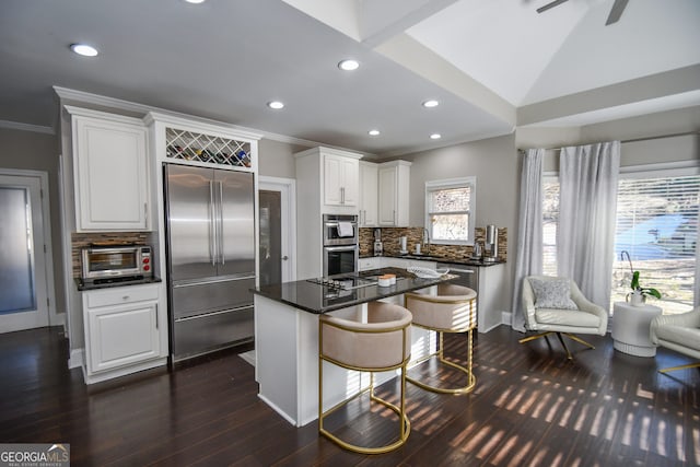 kitchen featuring white cabinetry, stainless steel appliances, tasteful backsplash, a breakfast bar area, and a kitchen island