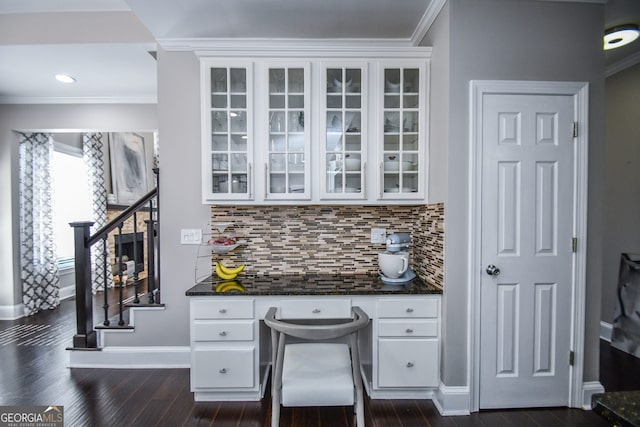 home office featuring dark hardwood / wood-style flooring, built in desk, and crown molding