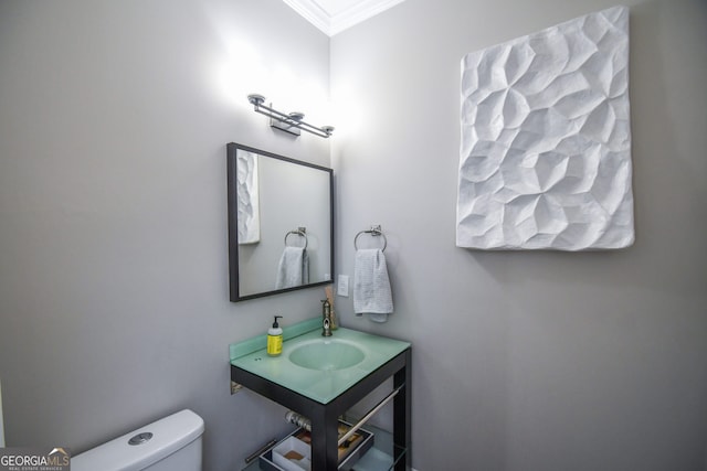 bathroom with toilet, ornamental molding, and sink