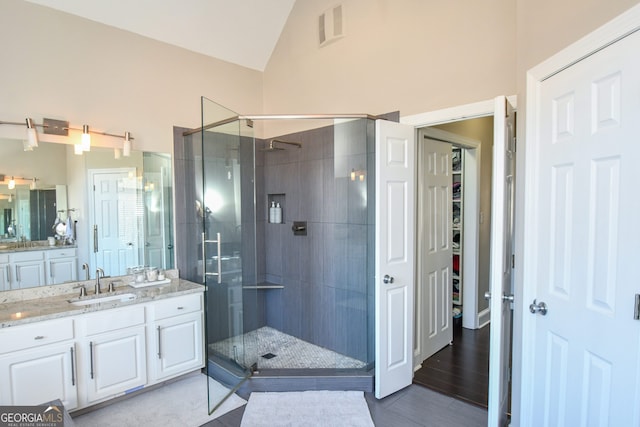 bathroom with vanity, a shower with shower door, and lofted ceiling