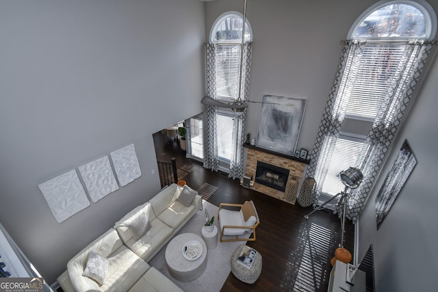 living room with a fireplace, a towering ceiling, and dark wood-type flooring