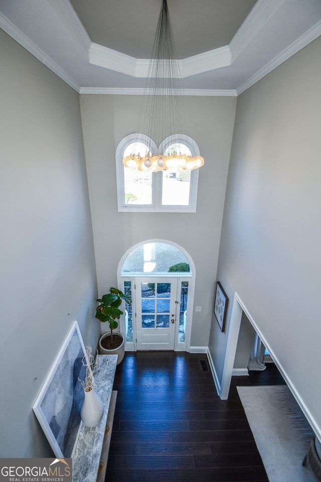 entryway featuring a towering ceiling, a chandelier, dark hardwood / wood-style floors, and ornamental molding