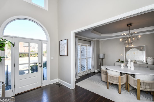 entrance foyer featuring a tray ceiling, crown molding, dark wood-type flooring, and a notable chandelier