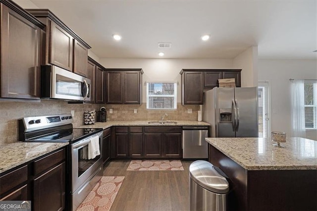 kitchen featuring sink, a kitchen island, light stone countertops, light hardwood / wood-style floors, and stainless steel appliances