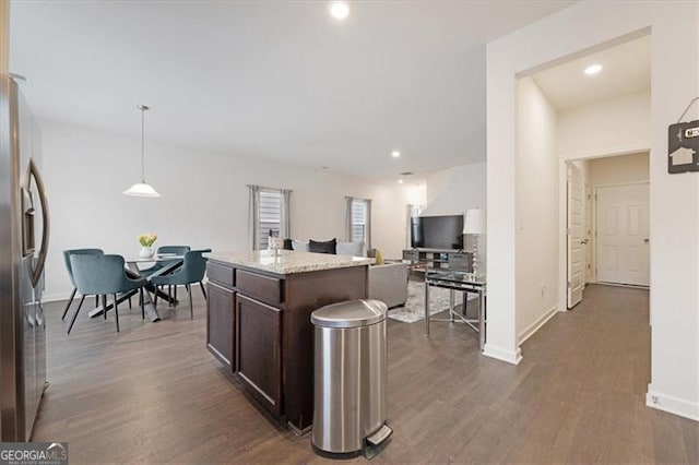 kitchen with a center island, dark wood-type flooring, stainless steel fridge, pendant lighting, and dark brown cabinets