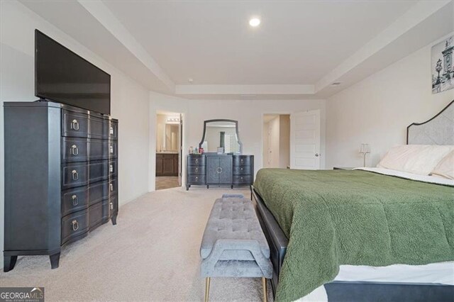 carpeted bedroom with ensuite bathroom and a raised ceiling