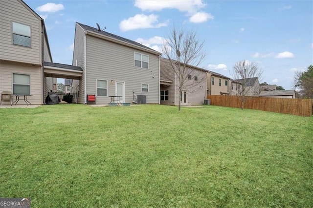 rear view of house featuring central AC and a lawn