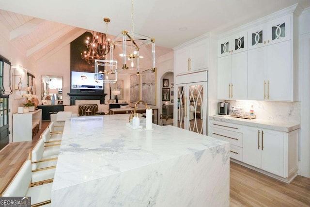 kitchen featuring paneled fridge, white cabinets, and decorative light fixtures